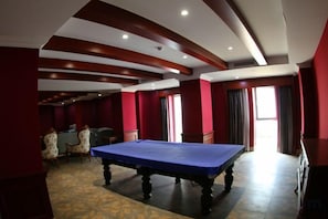 Une table de billard dans une pièce aux murs rouges et au tapis à motifs.
