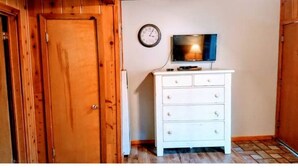 A room with a wooden door, a white dresser, a television, and a wall clock. - 01-The Cascade Falls studio at the Washoe (South Lake Tahoe)