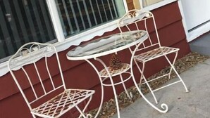 Ein Zimmer mit einem großen Fenster, einer weißen Tür und einem kleinen, weißen Tisch mit zwei Stühlen.