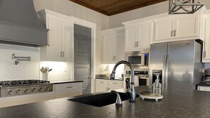 Une cuisine moderne avec des meubles blancs, des appareils en acier inoxydable et un plan de travail en granit noir.