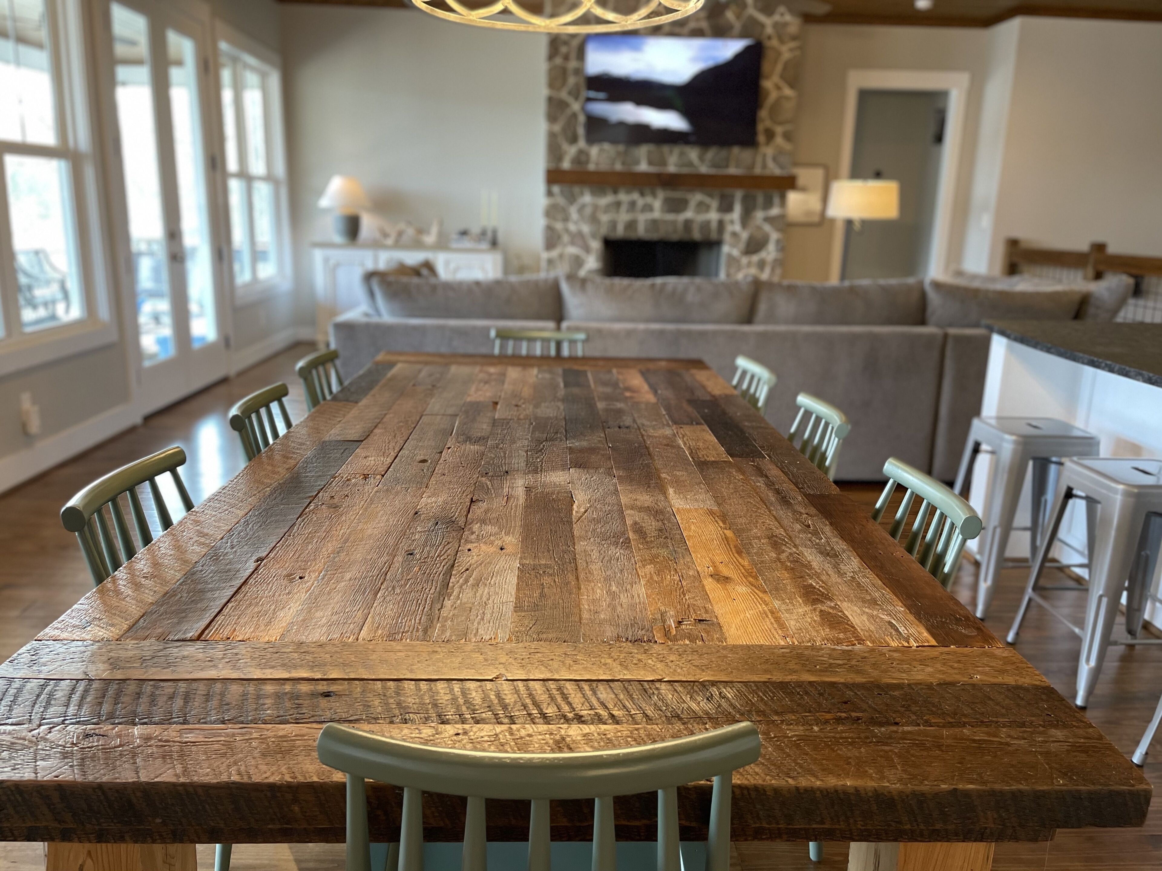 A large wooden dining table with chairs, a stone fireplace, and a television mounted on the wall.