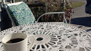 A white outdoor table with a coffee cup, a patterned pillow, and a chair. - Comfy Farmstay. Les Cheneaux Islands, Near to Mackinac Is., fresh eggs. Trails. (Hessel)