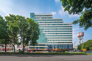 A multi-story building with a glass facade, surrounded by trees and a water tower in the background. - Hello Light Hotel (Guangzhou Yantang Metro Station) (Guangzhou)