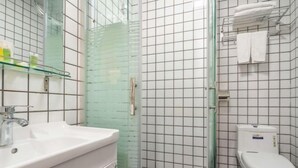 Ein Badezimmer mit Duschkabine aus Glas, einem weißen Waschbecken und einer Toilette.