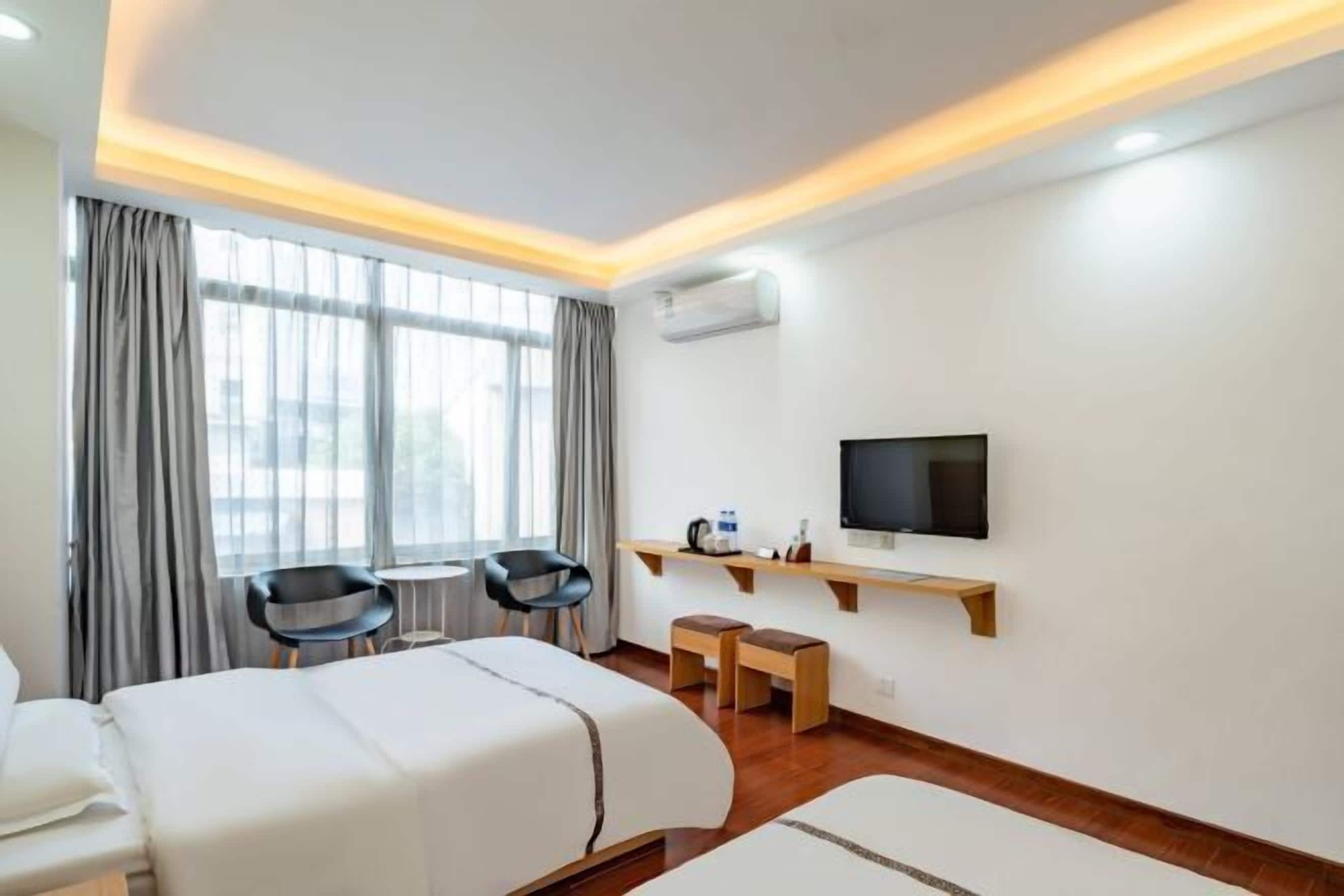 Una habitación de hotel con dos camas, televisión, escritorio y silla.