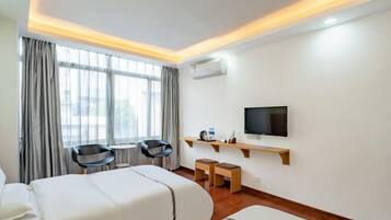 Una habitación de hotel con dos camas, televisión, escritorio y silla.