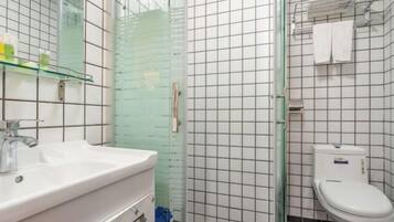 A bathroom with a glass shower enclosure, a white sink, and a toilet.
