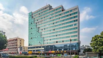 Un hotel de varios pisos con fachada moderna de vidrio, situado en una esquina con cielo despejado.