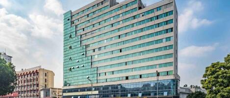 A multi-story hotel with a modern glass facade, located at a street corner with a clear sky.