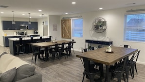 A modern kitchen with dark cabinets, a central island, and a dining area with a wooden table and black chairs. - NEW! Countryside Retreat Home with Space for Entertaining, Weddings and More! (Minster)