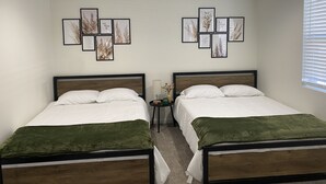 A room with two beds, each with a wooden frame and white bedding. There are framed botanical prints on the wall above the beds. - NEW! Countryside Retreat Home with Space for Entertaining, Weddings and More! (Minster)