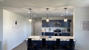 A modern kitchen with dark cabinets, a central island with bar stools, and pendant lighting. - NEW! Countryside Retreat Home with Space for Entertaining, Weddings and More! (Minster)