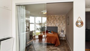 Un dormitorio moderno con cama, mesita de noche y vistas al balcón a través de un ventanal corredero.