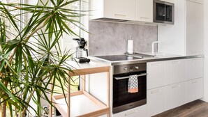 Una cocina moderna con armarios blancos, un lavamanos de acero inoxidable, un horno empotrado y un microondas.