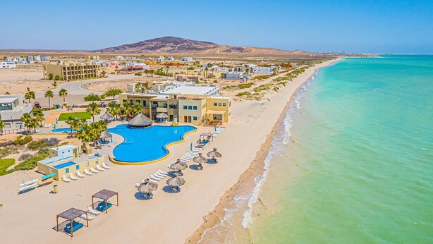 Ein Küstenresort mit Pool, Strand und Bergblick.