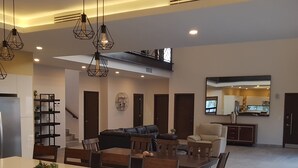 Eine geräumige Küche mit einer zentralen Kochinsel, ein Essbereich mit Stühlen und ein Wohnzimmer mit Sofas.