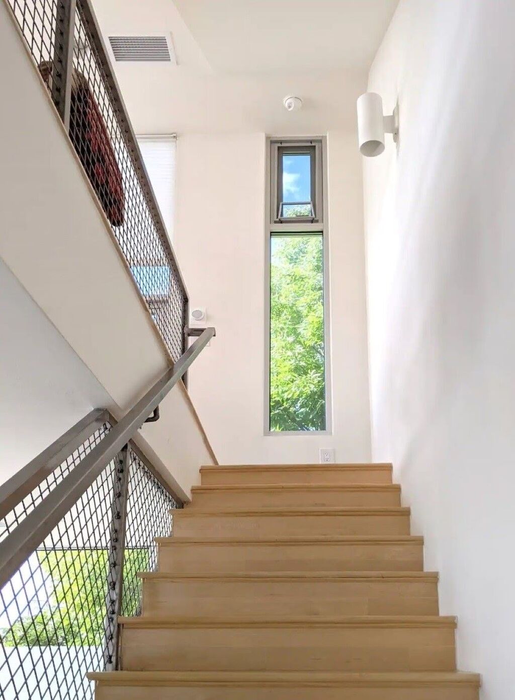 Eine Treppe mit Metallgeländer und einem Fenster am oberen Ende.