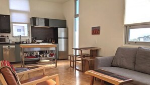A modern living room with a grey sofa, wooden coffee table, and a dining area with a wooden table and chairs. - The Tower - A Mountain View Escape (Santa Fe)