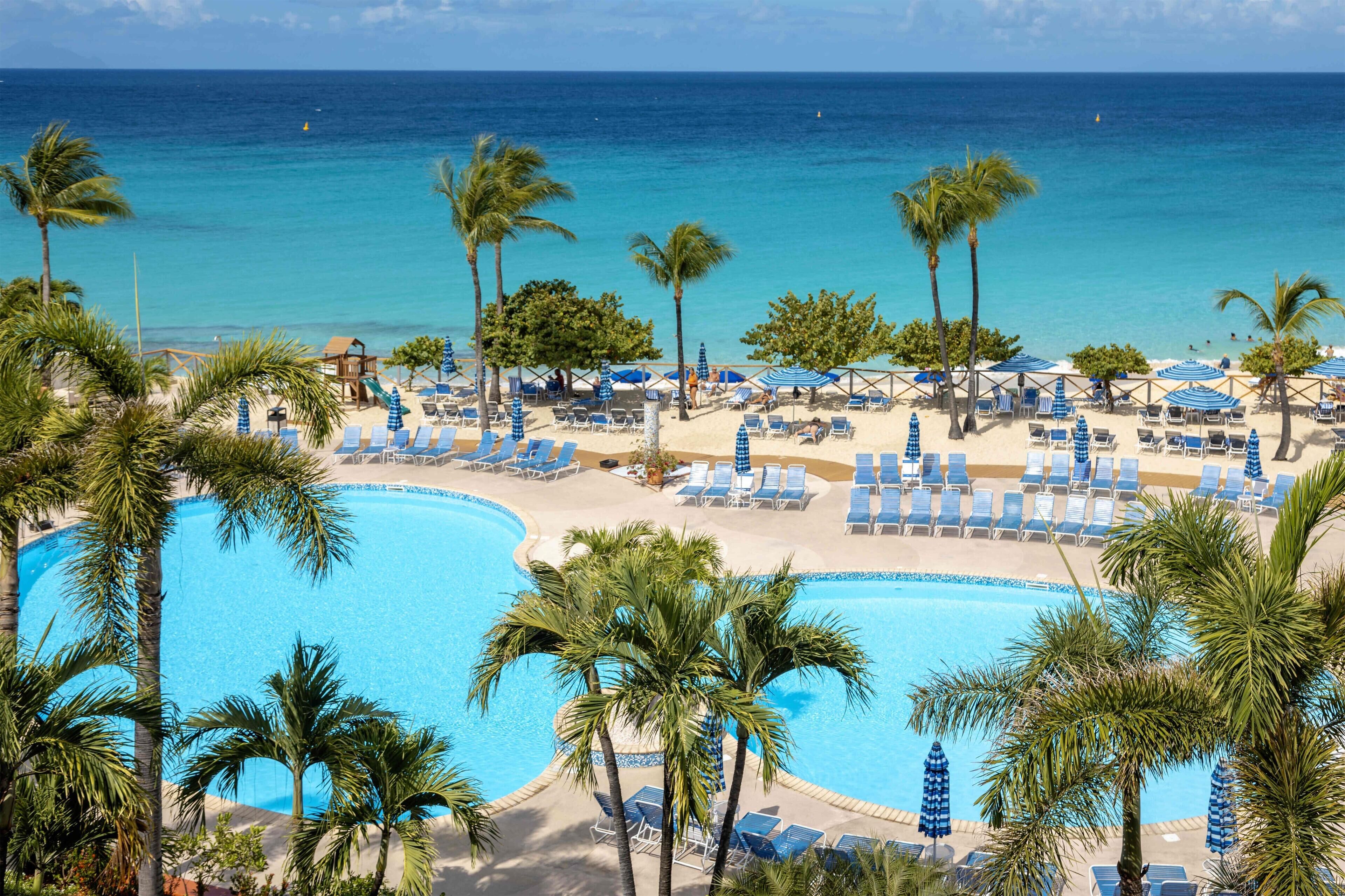 Ein Resort mit großem Pool, Liegestühlen und Palmen.