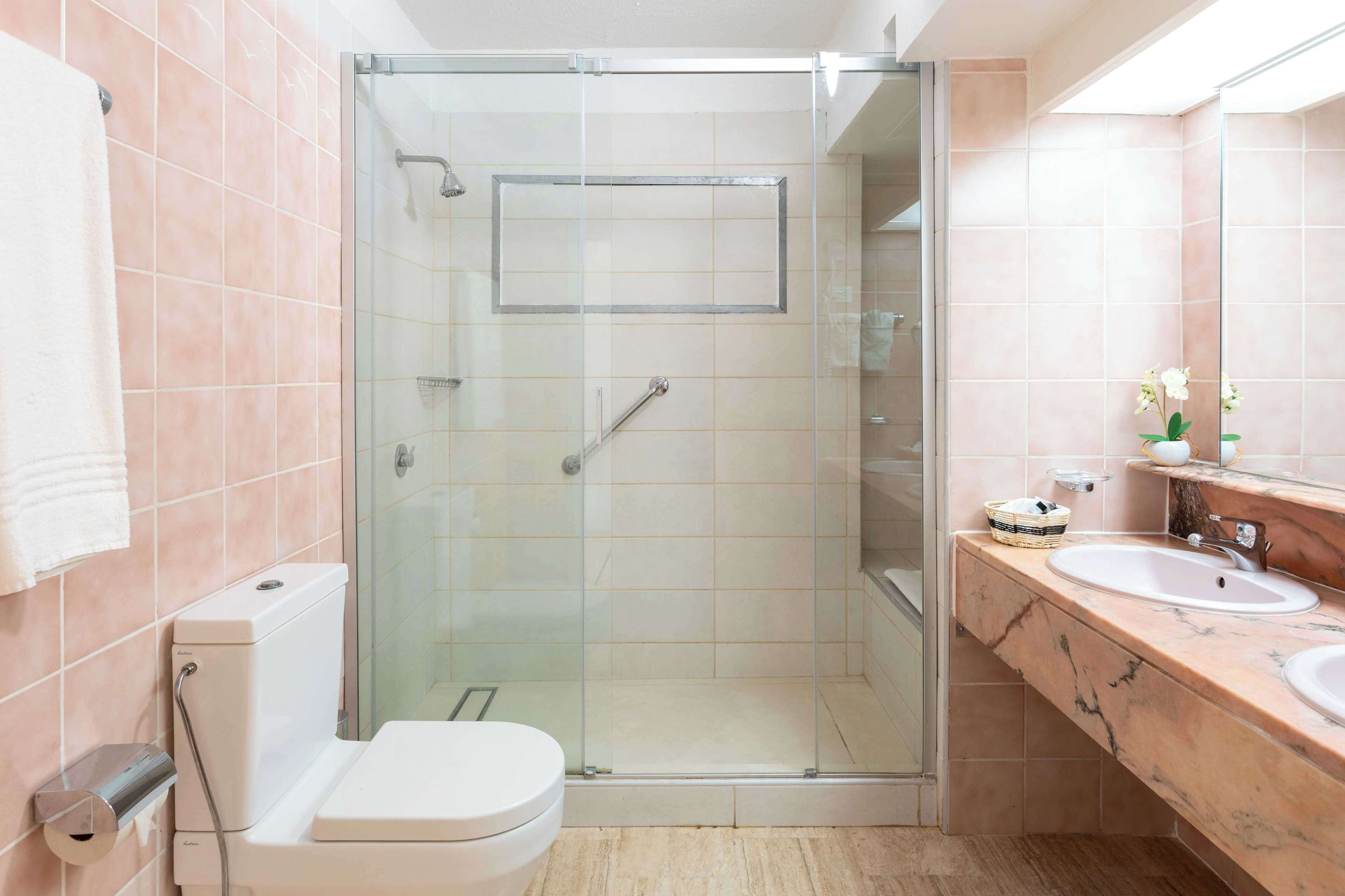 A bathroom with a glass-enclosed shower, a toilet, and a vanity with two sinks.