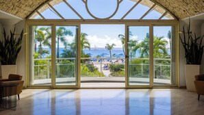 Amplia habitación con un gran ventanal que da a un balcón con vistas a la playa y al océano.