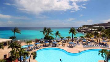 Alberca al aire libre, sombrillas en la alberca y camastros