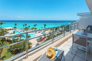 A balcony with a view of a beach and pool area, including lounge chairs and umbrellas. - Royal Islander Resort La Plage (Lowlands)
