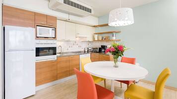 Una cocina moderna con microondas, horno y refrigerador. Hay una mesa de comedor con sillas y un florero con flores.