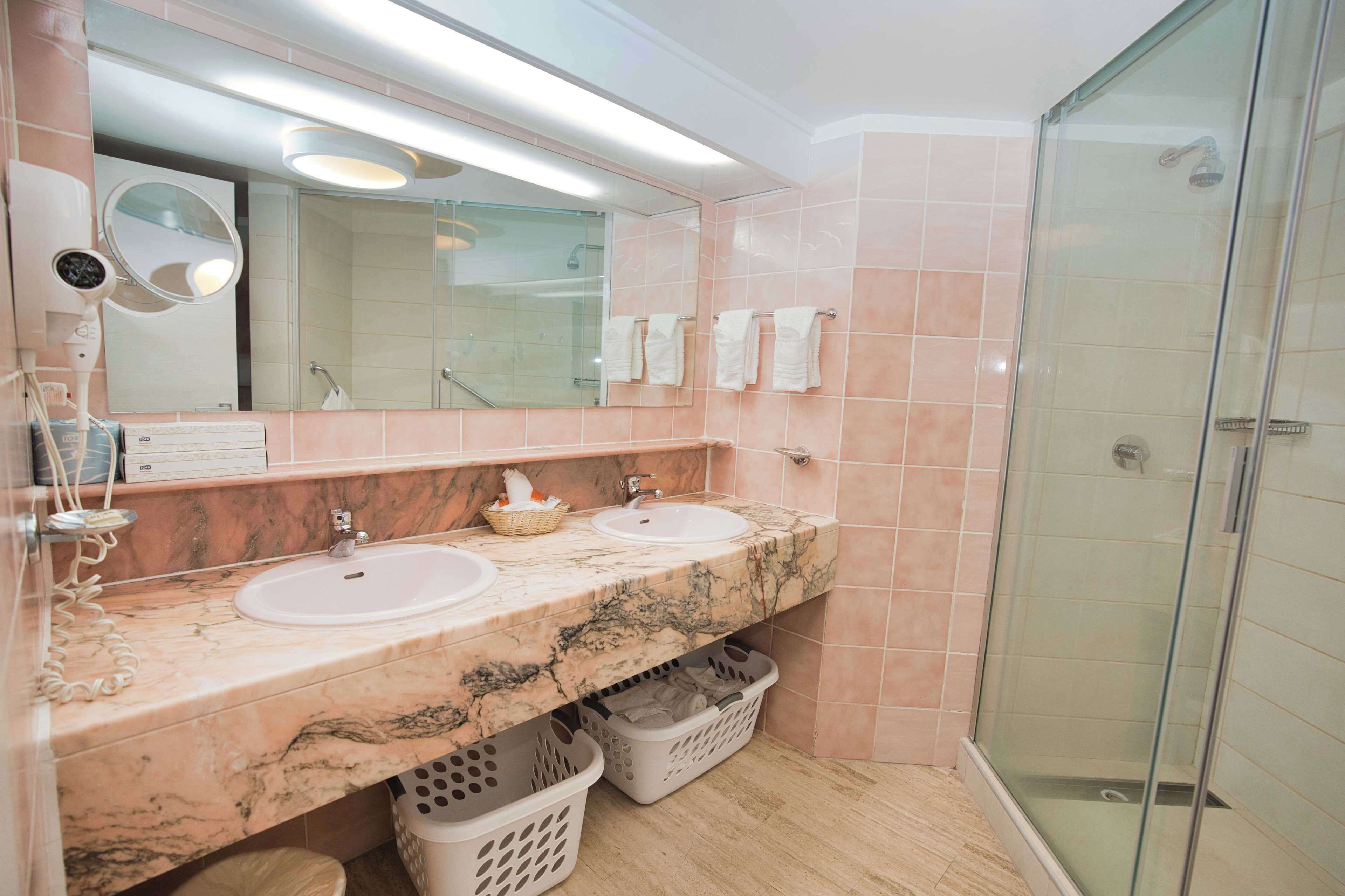 Un bagno con due lavandini, uno specchio grande e una cabina doccia in vetro.