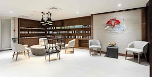 A modern spa reception area with a wooden reception desk, multiple seating options, and a wall displaying a logo and product shelves.