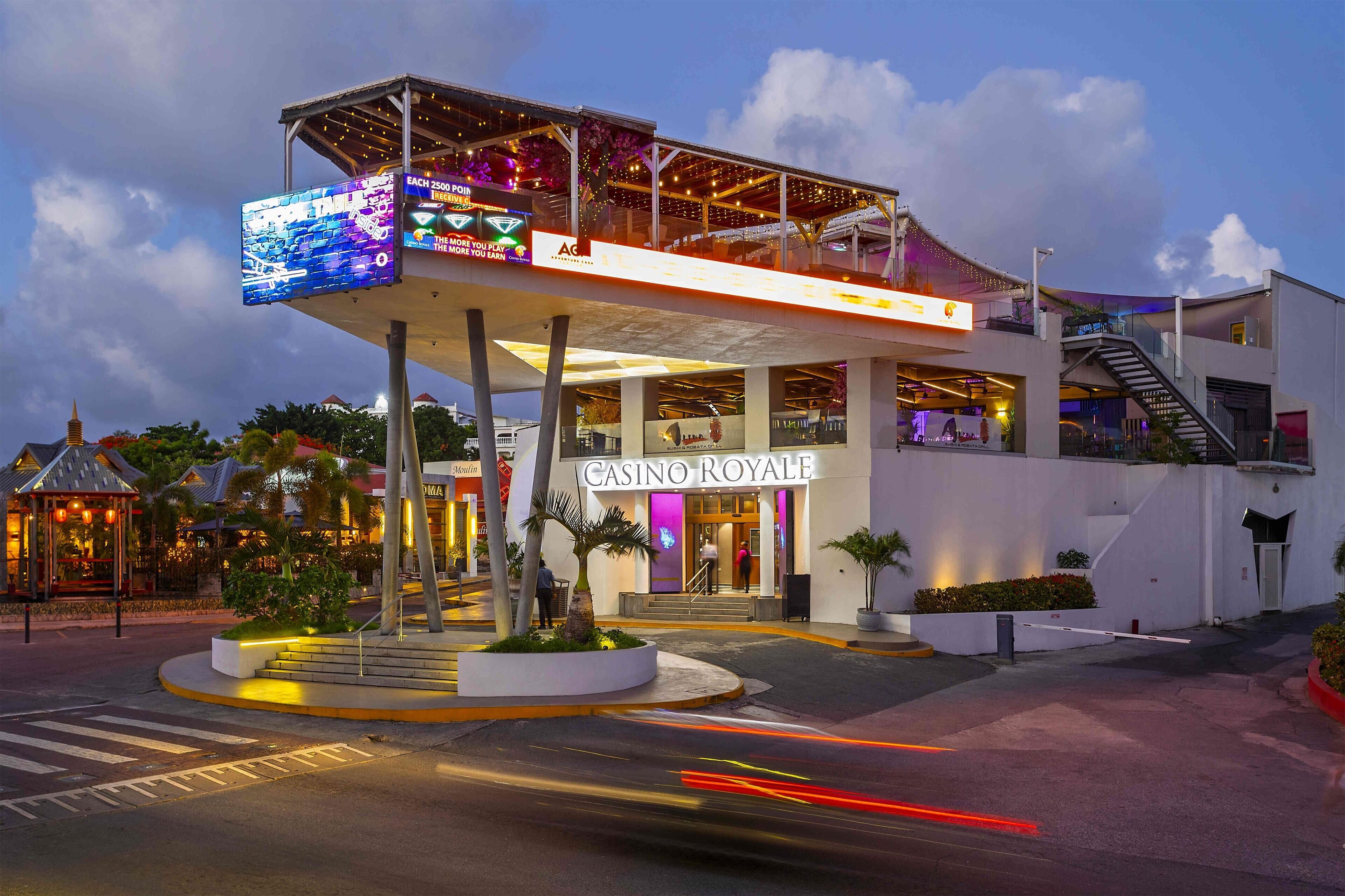 A casino with a prominent entrance, outdoor seating area, and a digital sign.