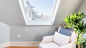 A room with a skylight, a white sofa, and a potted plant. - Walk to Space Needle Vintage View House with King Bed (Seattle)