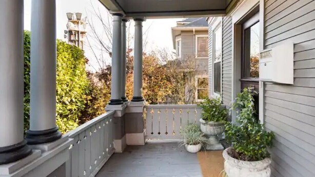 A covered porch with columns, potted plants, and a mailbox. - Walk to Space Needle Vintage View House with King Bed (Seattle)