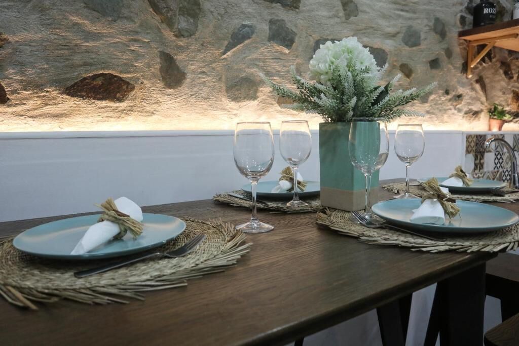 Une table  à manger dressée avec des assiettes, des verres et un vase de fleurs.