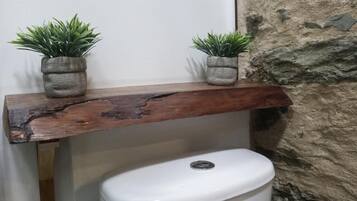 Ein rustikales Holzregal mit zwei Topfpflanzen auf einem weißen Toilettenbecken.