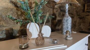 A table with a vase of green foliage, a glass candle holder, a decorative lamp, and a small figurine.