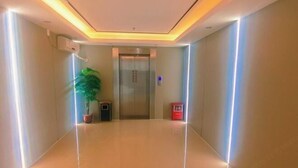 A hallway with a shiny floor, a potted plant, an elevator, and a red mailbox. - Hengshan Hotel (Taishan)