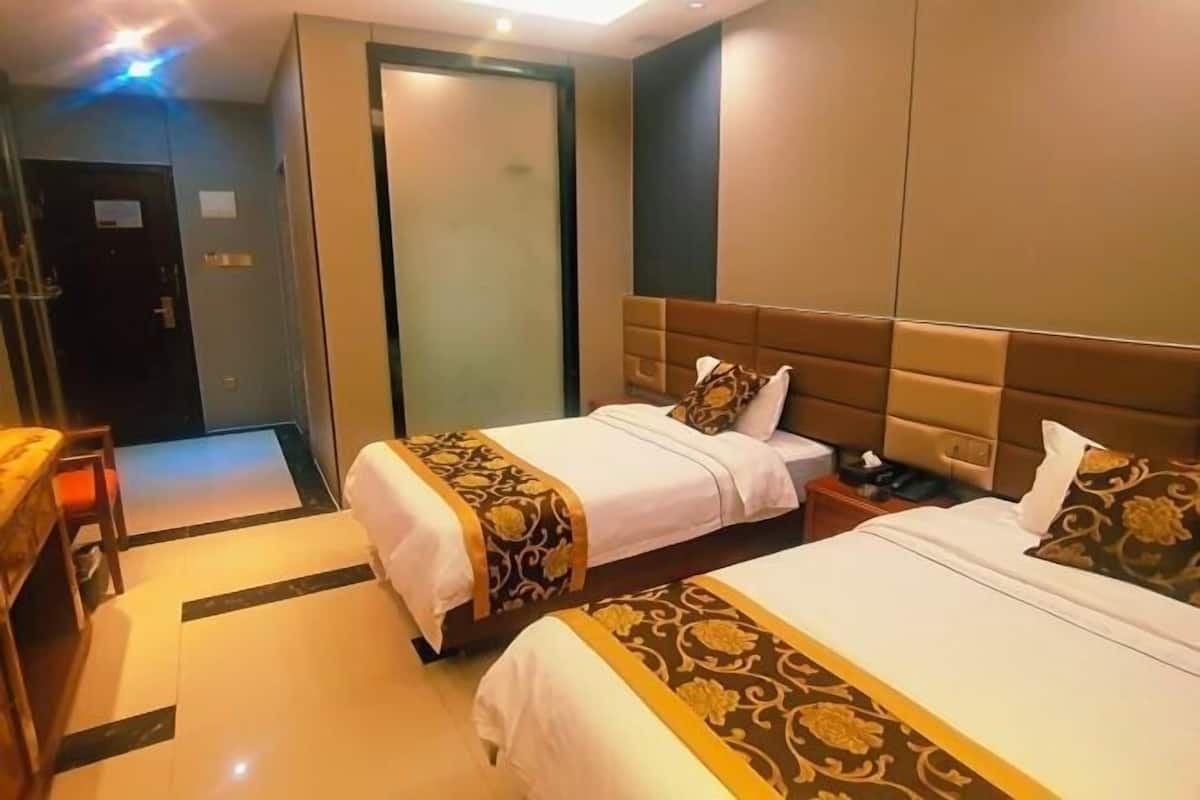 Habitación de hotel con dos camas, un escritorio y un armario.