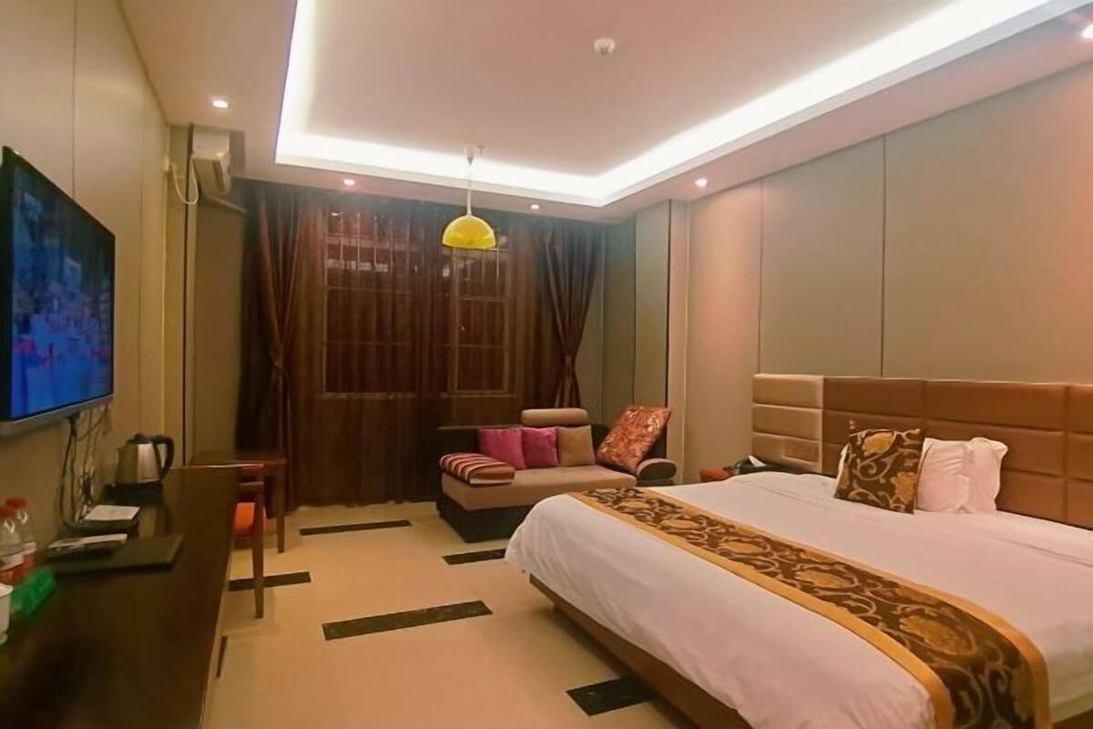 Una habitación de hotel con una cama, un escritorio, un televisor y una ventana con cortinas.