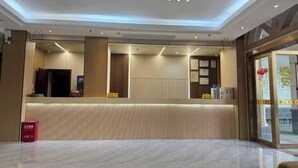 A hotel reception area with a modern design, featuring a reception desk, a waiting area, and a view of the outside through large glass doors. - Hengshan Hotel (Taishan)