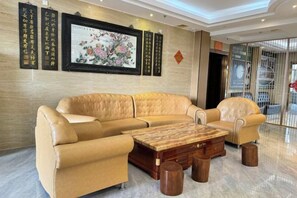 A modern hotel lobby with a beige leather sofa, a wooden coffee table, and a framed artwork on the wall. - Hengshan Hotel (Taishan)