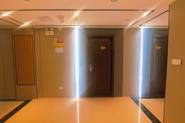 A hotel corridor with a reception area, a door with a sign, and a wall-mounted light fixture.