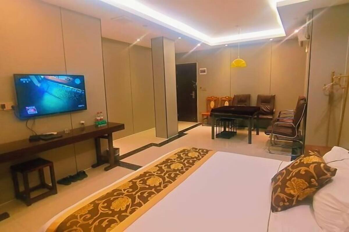 Una habitación de hotel con una cama, televisor, escritorio y zona de comedor.