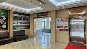 A hotel lobby with a reception desk, a seating area, and an elevator. - Hengshan Hotel (Taishan)
