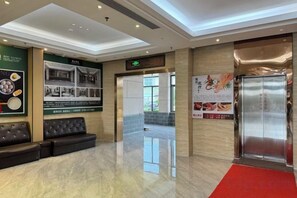 A hotel lobby with a red carpet, a reception desk, a seating area, and a wall with informational posters. - Hengshan Hotel (Taishan)