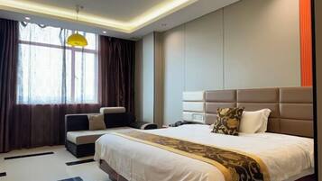 Una habitación de hotel moderna con una cama grande, un sofá, un escritorio y un ventanal con cortinas.