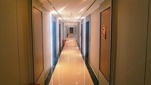 A long, narrow hotel corridor with a shiny, reflective floor and doors on both sides. - Hengshan Hotel (Taishan)