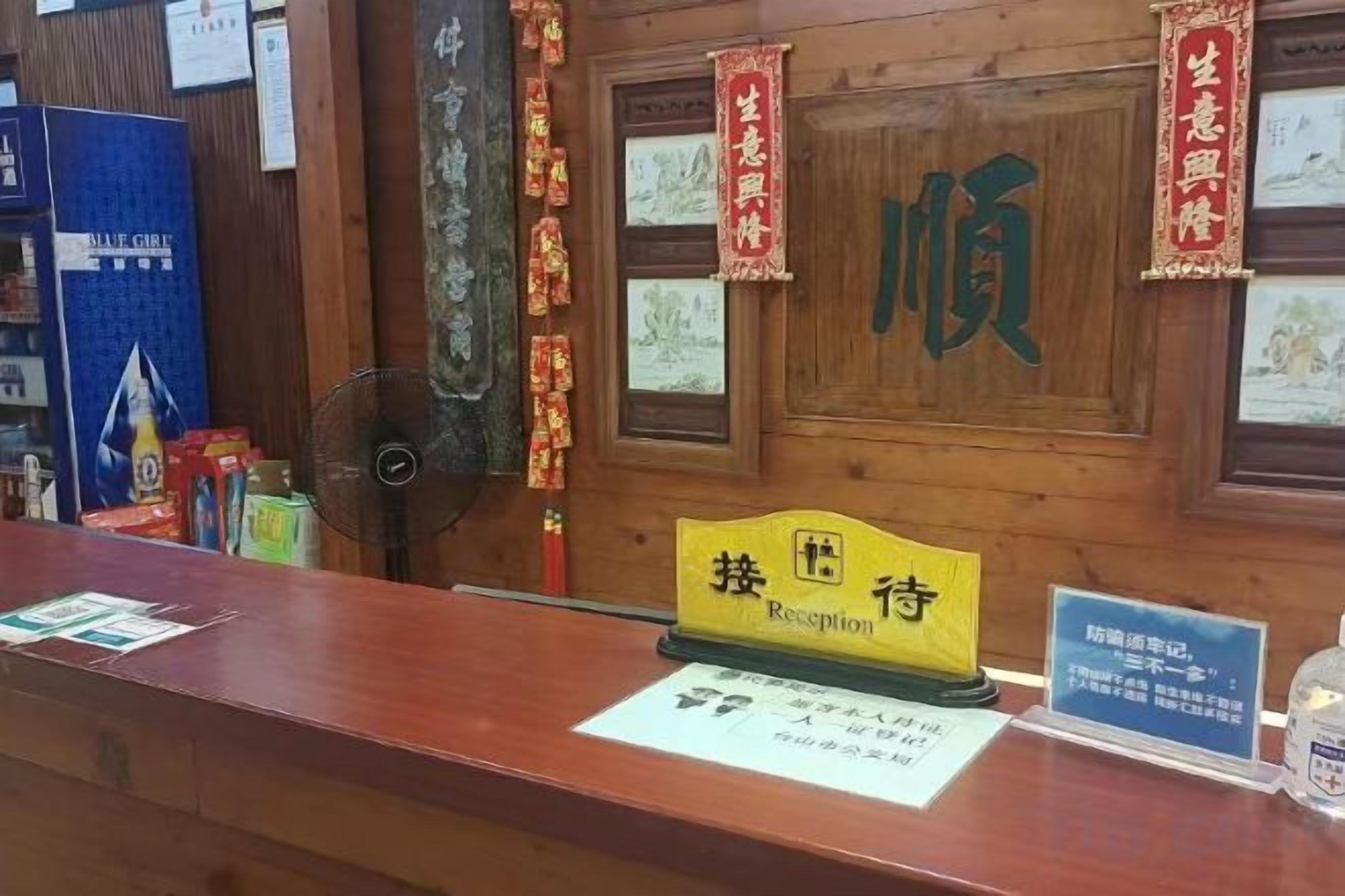 Un comptoir d’accueil avec une pancarte indiquant « Réception » et un mur en bois orné de caractères chinois.