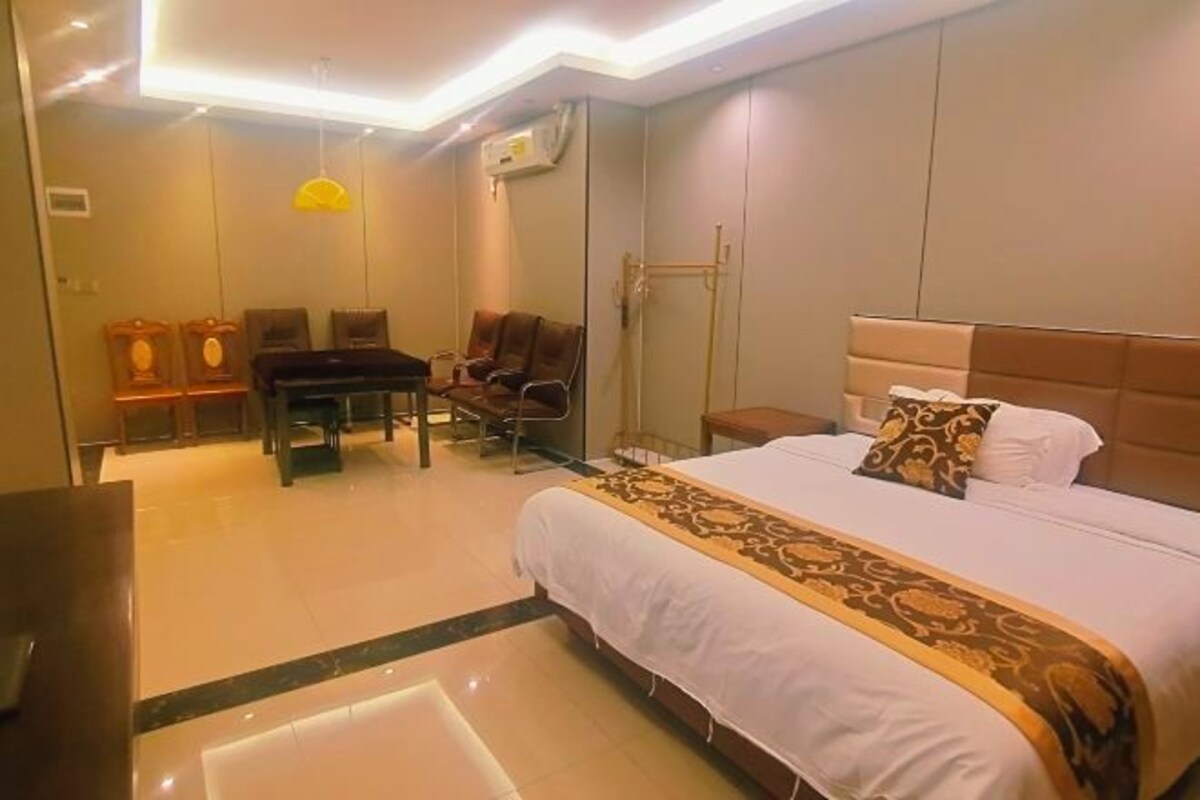 A hotel room with a large bed, a desk, two chairs, and a small table.