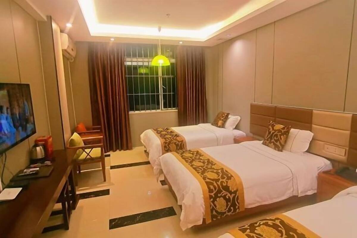 Habitación de hotel con dos camas, un escritorio con televisor y una ventana con cortinas.